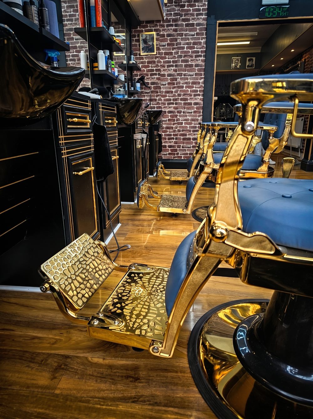 Inside the shop — gold barber chairs and brick wall